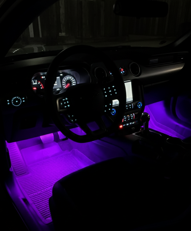 Car interior with purple LED lights illuminating the dashboard and floor.